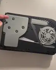 Benutze den Kreuzschlitzschraubendreher um die Schraube, die innerhalb des schwarzen Aufklebers liegt, im Uhrzeigersinn zu drehen.