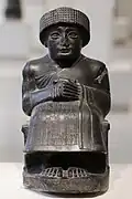 Diese steinerne Statue ist mit Keilschrift beschriftet.