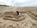 Hier baut jemand in Südafrika Sand-Statuen oder Strandskulpturen.