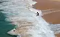 Jemand springt in die Wellen, an einer Meeresküste in Portugal.