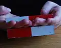 Der untere Magnet wird vom oberen angezogen, obwohl die Finger dazwischen sind.