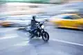 Das Motorrad bewegt sich rasch vor dem unscharfen Hintergrund.