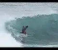 Ein Surfer nutzt die Kraft der Welle, um sich vorwärts zu bewegen.