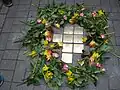 Die Stolpersteine sind fertig verlegt, und die Zuschauer legen ihre Blumen dazu.