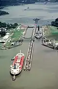 Hier fahren ein Kriegsschiff und ein Frachter durch den Panamakanal.