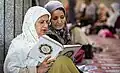 Zwei Musliminnen mit einem Hidschab lesen im Koran.