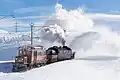 Ein Foto aus der Schweiz: Der Eisenbahnzug „Berninakrokodil“ fährt über den Berninapass und schiebt dabei den Schnee weg.