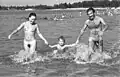 Eine Familie läuft nackt durchs Wasser.