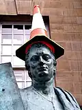 Eine Statue eines englischen Philosophen. Weniger ernst ist der Verkehrskegel, den jemand auf den Kopf gesetzt hat.