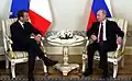 Der Präsident von Frankreich, Emmanuel Macron, sitzt hier links. Der andere Mann ist Wladimir Putin, der russische Präsident.