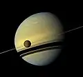 Der kleine schwarze Kreis ist der Mond Titan, mit dem Saturn im Hintergrund