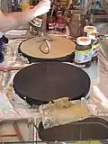 Der Teig der Crêpes wird über die Pfanne gewischt, um ihn dünn zu machen.