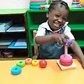 Ein Kind in einer Montessori-Schule in Nigeria lernt durch das Spielen mit bunten Ringen.