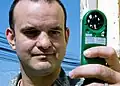 Ein Mann misst die Windgeschwindigkeit mit einem Hand-Anemometer.