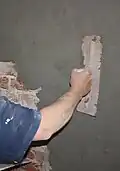 Dieser Bauarbeiter verputzt gerade eine Backstein-Mauer.