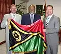 Der Präsident zeigt mit ausländischen Diplomaten die Flagge. Das Symbol ist der Stoßzahn eines Keilers.