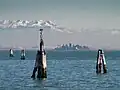 Blick zum Festland. Man sieht im Wasser die Insel Tessera und ganz hinten die Alpen.