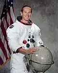 Der amerikanische Astronaut Charles Moss Duke mit einem Globus des Mondes.