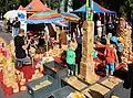 Auf einem Straßenfest: Kinder spielen mit großen Blauklötzen aus Holz.