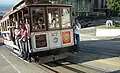 Auf der Straßenbahn fahren Passagiere auf dem Trittbrett mit.