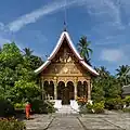 Ein Tempel in Laos, daneben ein buddhistischer Mönch. Luang Prabang ist ein Weltkulturerbe.