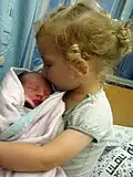 Ein dreijähriges Mädchen mit dem neugeborenen Bruder