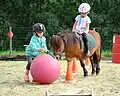 Zwei Kinder spielen mit einem Pony.