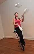 Diese Frau jongliert mit Keulen, während sie Einrad fährt.