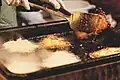 Auf einem Weihnachtsmarkt: Ein Kartoffelpuffer wird gerade gewendet.