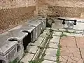 So sahen öffentliche Toiletten bei den alten Römern aus. Man saß nebeneinander und unterhielt sich.