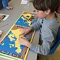 Dieser Schüler spielt mit einer Landkarte und lernt so die Länder Europas.