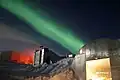 Während der langen Polarnacht kann man manchmal Polarlichter sehen, wie hier über einer Forschungsstation in der Antarktis. Diese Leuchterscheinungen am Himmel entstehen in den Polarregionen.