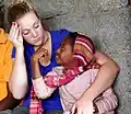 Ein äthiopisches Kind lernt mit einer Frau eine Gebärdensprache; Das Kind sitzt auf dem Schoß der Frau.