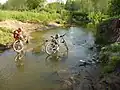 Diese beiden Radfahrer waten durch ein Gewässer in Russland.