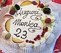 Auf dieser Geburtstagstorte für Monica steht das italienische Wort „auguri“. Es bedeutet: Glückwünsche.