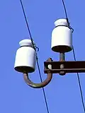 Telefonleitungen werden über Isolatoren aus Keramik geführt.