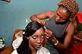 Eine Hairstylistin in Nigeria kümmert sich um eine Braut.