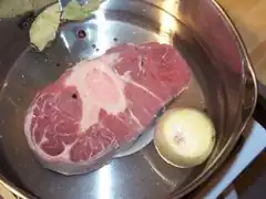 Die Beinscheibe im Topf auf eine Untertasse legen.