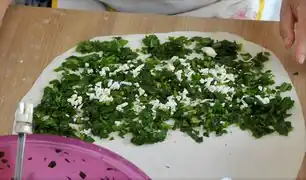 Den Teig belegen, hier mit Spinat und Feta-Käse