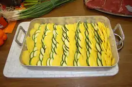 Die Kartoffel- und Zucchinischeiben abwechselnd dachziegelartig schichten und