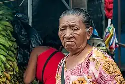 Older woman with a disappointed look on her face in a busy market place.